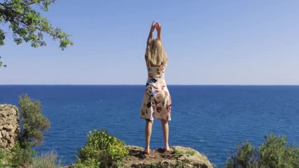 Volwassen Vrouw Staat Rots Tegenover Zee Doet Yoga Oefeningen Tussenschot — Stockvideo