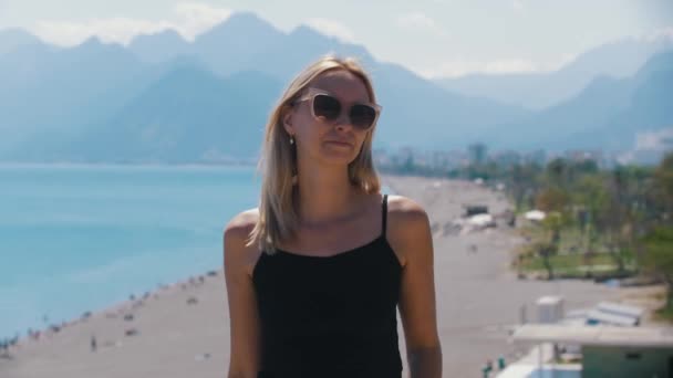 Блондинка Стоїть Тлі Пляжу Знімає Свої Сонцезахисні Окуляри Середній Постріл — стокове відео