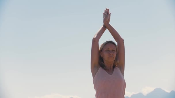 山を背景にヨガの練習をする大人の精神的な女性 ミッドショット — ストック動画