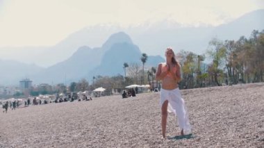 Yetişkin sarışın kadın çakıl taşı plajında yoga yapıyor. Orta çekim