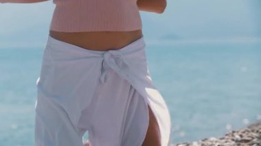 Yetişkin ruhlu kadın çakıl taşlarının üzerinde duruyor ve ellerini arkasına uzatıyordu. Orta çekim