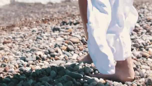 一个女人走在卵石上 走到海里 — 图库视频影像