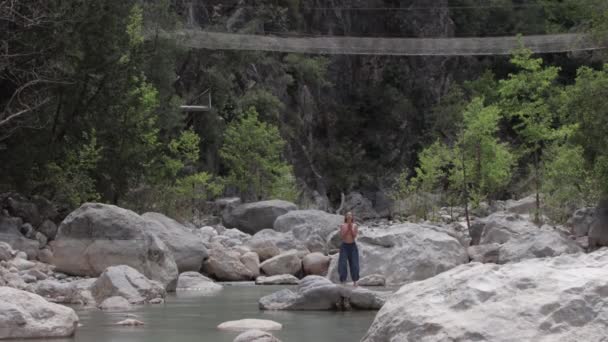 Geniş Açık Pantolonlu Bir Kadın Derenin Ortasındaki Kayanın Üzerinde Meditasyon — Stok video