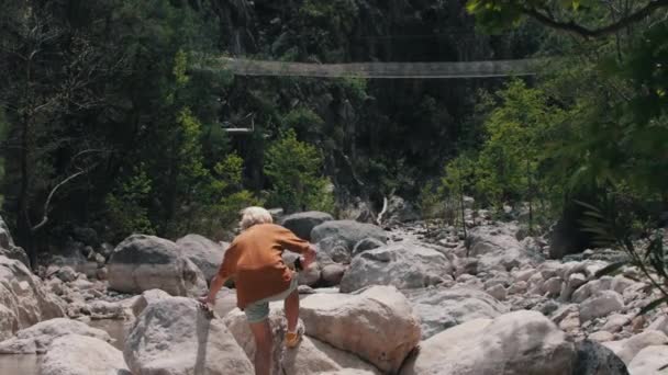 若い男が岩を登り 周囲の写真を撮る ミッドショット — ストック動画