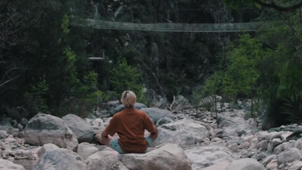 Giovane Seduto Sulla Roccia Circondato Dalla Foresta Meditando Mid Shot — Video Stock