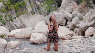 Yazlık elbiseli yetişkin bir kadın doğa üzerinde meditasyon yapıyor. Orta çekim