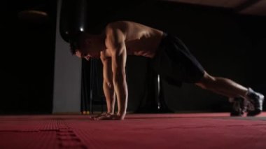 Fitness antrenmanı. Zeminde formasız bir adam çalışıyor. Orta çekim