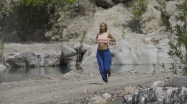 Su akıntısıyla yoga yapan kısa saçlı bir kadın meditasyon egzersizleri yapıyor. Orta çekim