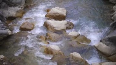 Kayalardan köpüren bir dere akıyor. Orta çekim