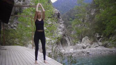 Dağlarda yoga yapan bir kadın basit jimnastik ve nefes egzersizleri yapıyor. Orta çekim