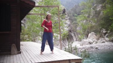 Göl kenarında yoga yapan, gözleri kapalı sallanan ruhani bir kadın. Orta çekim