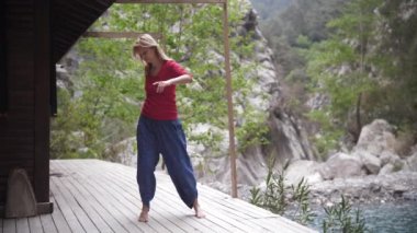 Göl kenarında yoga yapan, gözleri kapalı sallanan ruhani bir kadın. Orta çekim