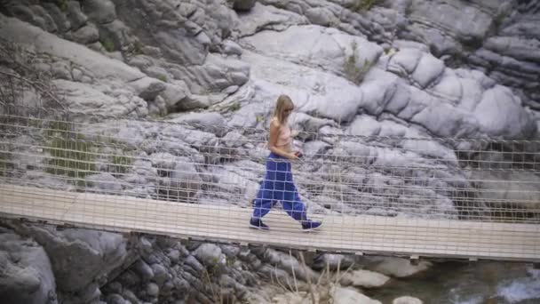 Взрослая Блондинка Идущая Веревочному Мосту Над Скалами Ручьем Средний Выстрел — стоковое видео