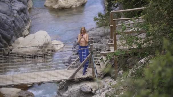 Volwassen Vrouw Staat Touwbrug Boven Beek Maakt Foto Haar Telefoon — Stockvideo