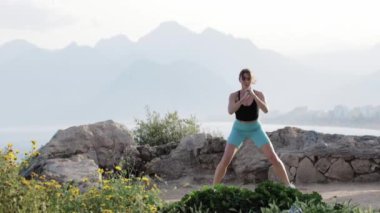 Kayalık bir yükseklikte spor yapan bir kadın. Orta çekim