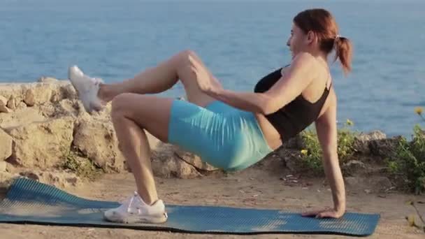 スポーツ屋外 フィットネス女性は海でヨガマットで運動をしています ミッドショット — ストック動画