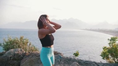 Sportif kadın tepeye doğru yürür ve saçını bağlar. Orta çekim
