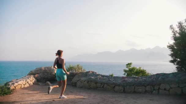 Młoda Kobieta Sportowych Ciuchach Biegnie Skalistego Ogrodzenia Wzgórzu Nad Morzem — Wideo stockowe