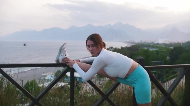 Eine Sportliche Frau Streckt Ihr Bein Zaun Auf Dem Hügel — Stockvideo
