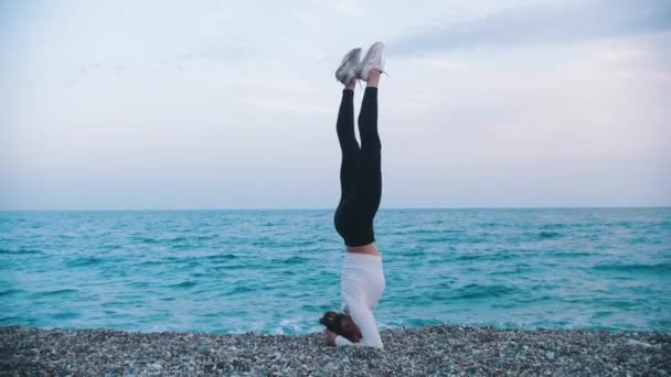 ペブルビーチの上に立っている体操の女性 ミッドショット — ストック動画