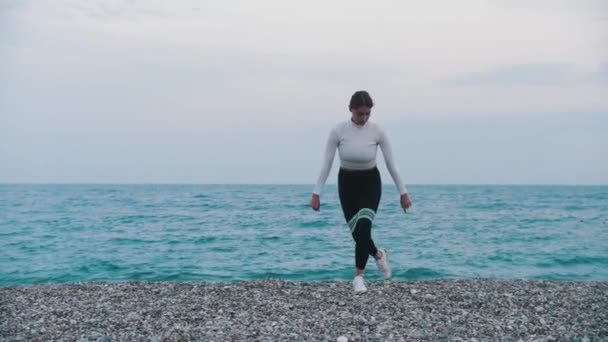 Žena Cvičí Elastickým Proužkem Mezi Stehny Oblázkové Pláži Střední Snímek — Stock video