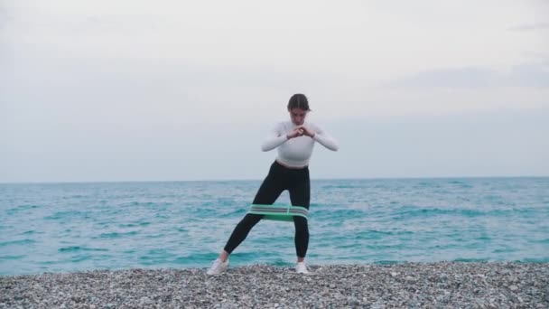 Žena Cvičící Elastickým Proužkem Mezi Nohama Oblázkové Pláži Střední Snímek — Stock video