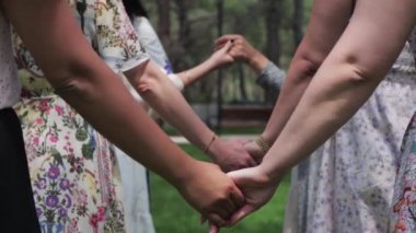 Women in traditional dresses holding hands at a folk festival. Mid shot