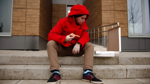 赤い服を着た男が国境に座ってピザを食べている ミッドショット — ストック写真