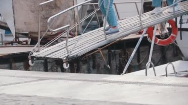 A man descends from a boat on a bridge. Mid shot