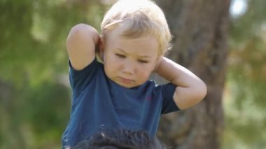 Anne, küçük oğlunu kocasının omuzlarından alıyor. Orta çekim