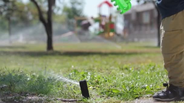 Little Boy Playing Plastic Spatula Water Sprinkler Mid Shot — Stockvideo