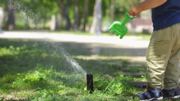 Little Boy Park Playing Plastic Spatula Water Sprinkler Mid Shot — Videoclip de stoc