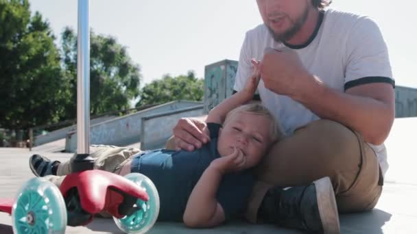 Маленький Хлопчик Батьком Сидить Підлозі Скейт Парку Середній Постріл — стокове відео