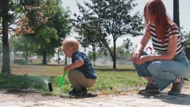 Little Boy Playing Water Sprinkler His Mother Sitting Nearby Mid — Vídeo de stock