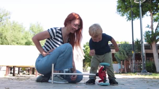 Little Boy Playing Wheels His Scooter His Mother Sitting Nearby — Stockvideo