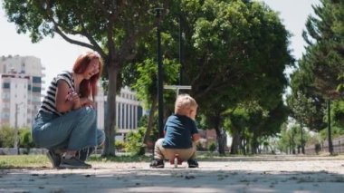 Küçük bir çocuk yerden bir scooter aldı ve annesiyle birlikte yürüyüşe çıktı. Orta çekim