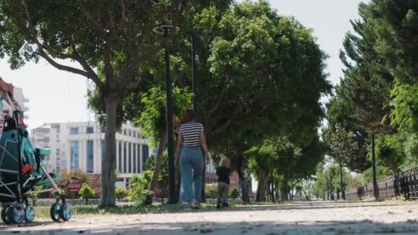 Young Family Walks Green Sidewalk Mid Shot — ストック動画