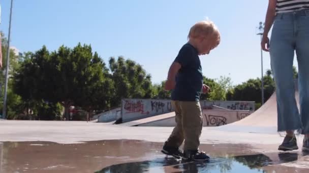 Little Boy His Mother Walks Puddles Skatepark Father Watching Mid — Stockvideo