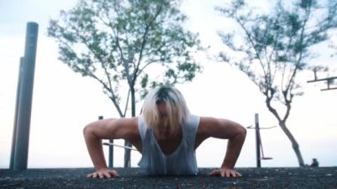 Young man doing push ups on the outdoors sports ground. Mid shot
