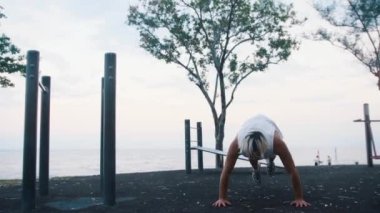 Bir adam spor parkında şınav çekip sıçrıyor. Orta çekim