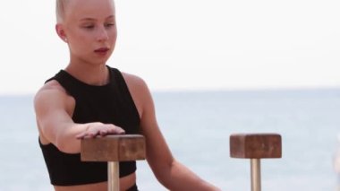 Deniz kenarındaki genç sarışın jimnastikçi tribünlere çıkıyor. Orta çekim