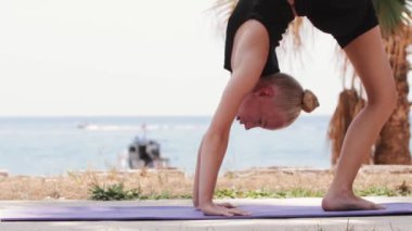 Sarışın, jimnastik yapan, vücudunu yoga minderinde çalıştıran bir kadın. Orta çekim