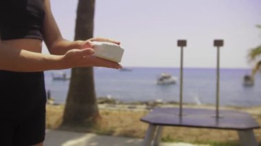Deniz kenarında jimnastik yapıyor. Elinde pudra tuğlası olan genç bir kadın. Orta çekim
