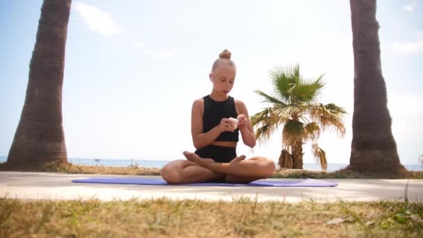 Young Female Gymnast Sitting Yoga Mat Puts Wireless Headphones Mid — Stockvideo
