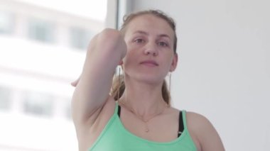 Woman does yoga in the studio - clasps her hands behind her back. Mid shot