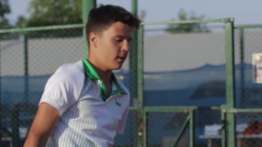 A young man forcefully hits a ball with a racket. Mid shot