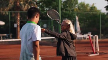 24-05-2022 TURKEY, ANTALYA: female tennis coach talks to her student and shows him the moves. Mid shot