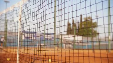 Shady net flutters in the wind on the court. Mid shot