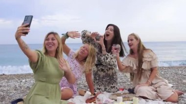 Smiling happy women taking selfie at the picnic on the beach. Mid shot