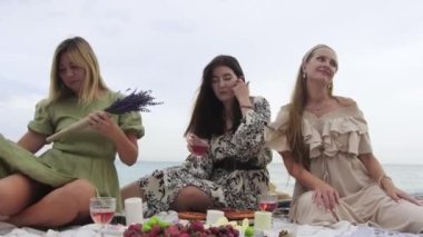 Pretty women on picnic by the beach. Mid shot